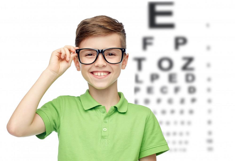 Young boy wearing glasses in front of an eye chart