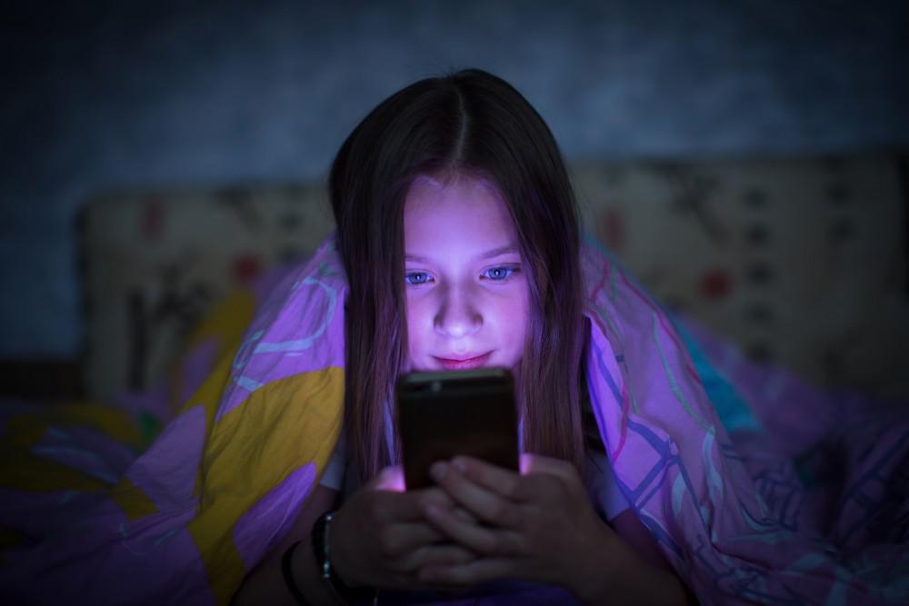 Child looking at a phone screen in the dark